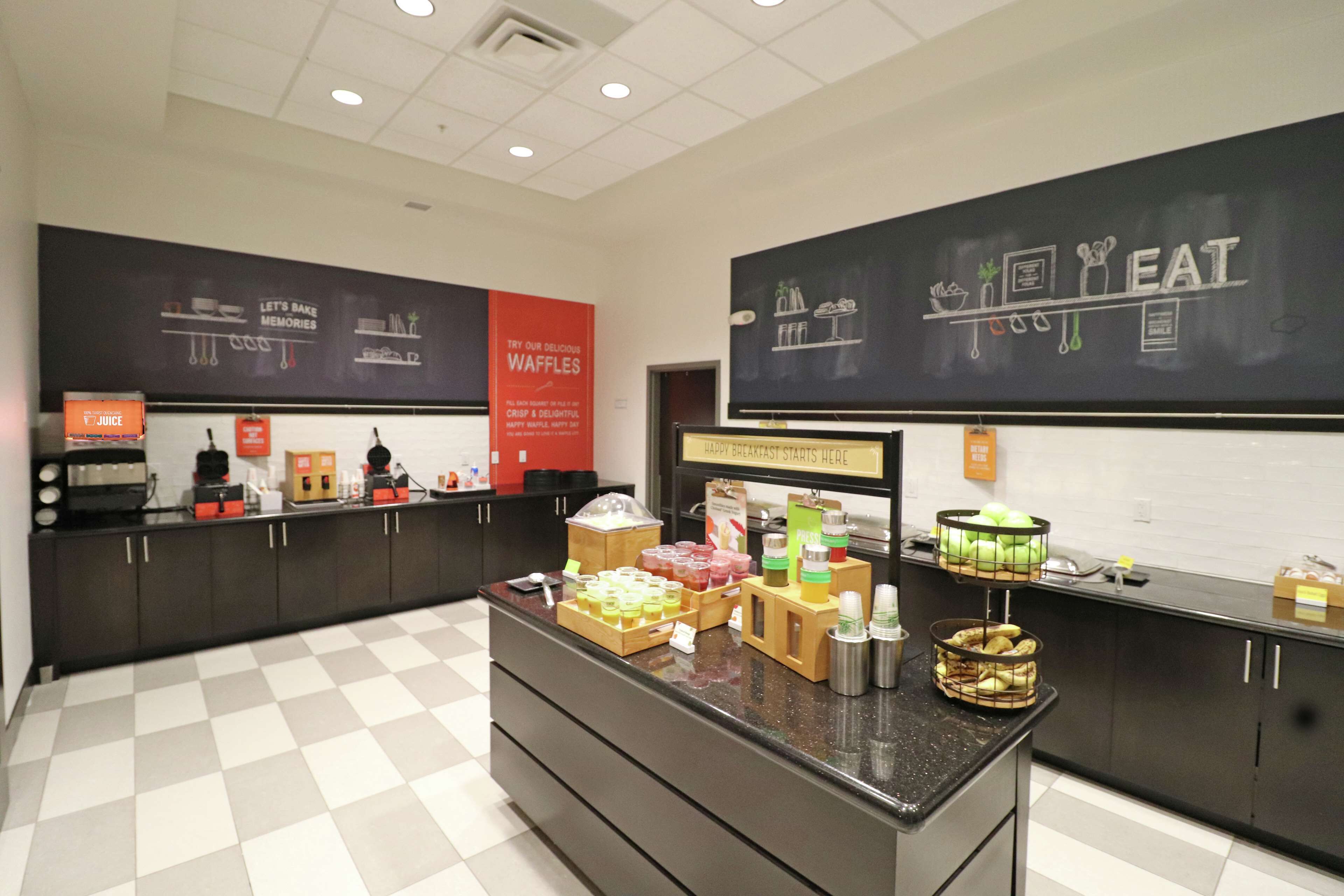 A breakfast area with a checkered floor, a counter with various food items, and chalkboard walls with food-related drawings and text.