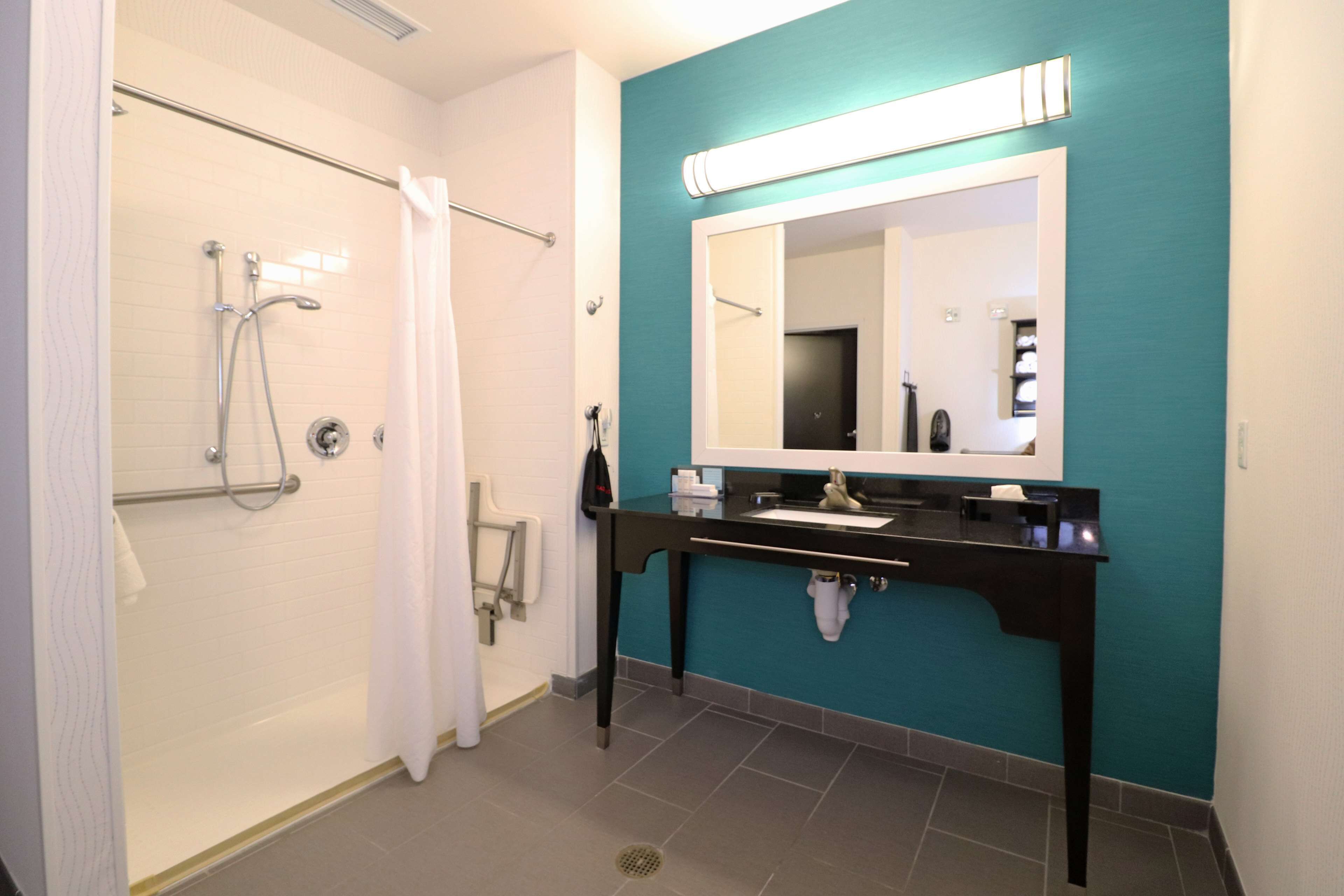 A bathroom with a shower, a sink, and a mirror.