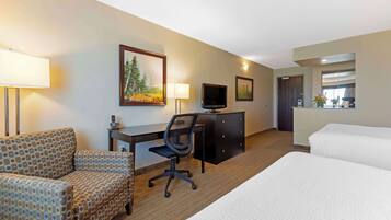 A hotel room with a bed, a desk with a chair, a television, and a dresser.