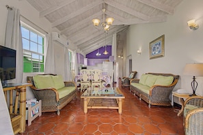 A spacious living area with wicker furniture, a glass coffee table, and a ceiling with exposed beams. - Best E Villas Prospect (Prospect)