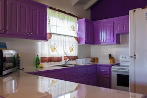 A kitchen with purple cabinets, a white refrigerator, a stove, and a microwave.