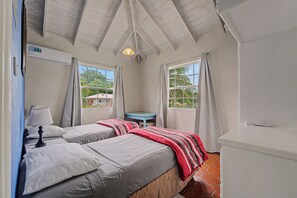 Une chambre avec deux lits, un bureau et une fenêtre avec des rideaux.