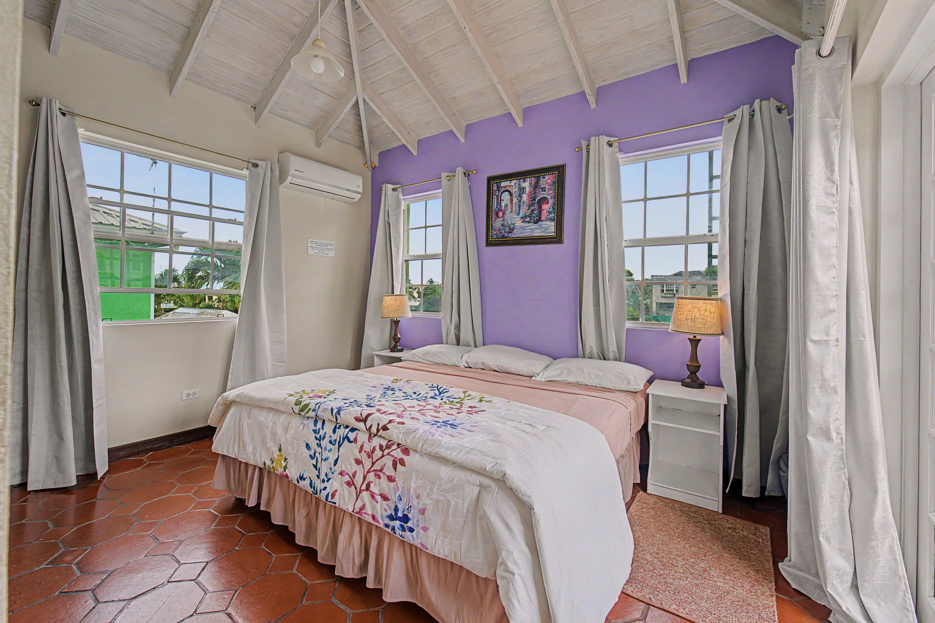 A bedroom with a bed, two bedside tables, a window, and a ceiling fan.