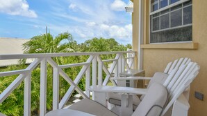 A balcony with white chairs and a table, overlooking a garden with palm trees and a clear sky. - Best E Villas Prospect (Prospect)