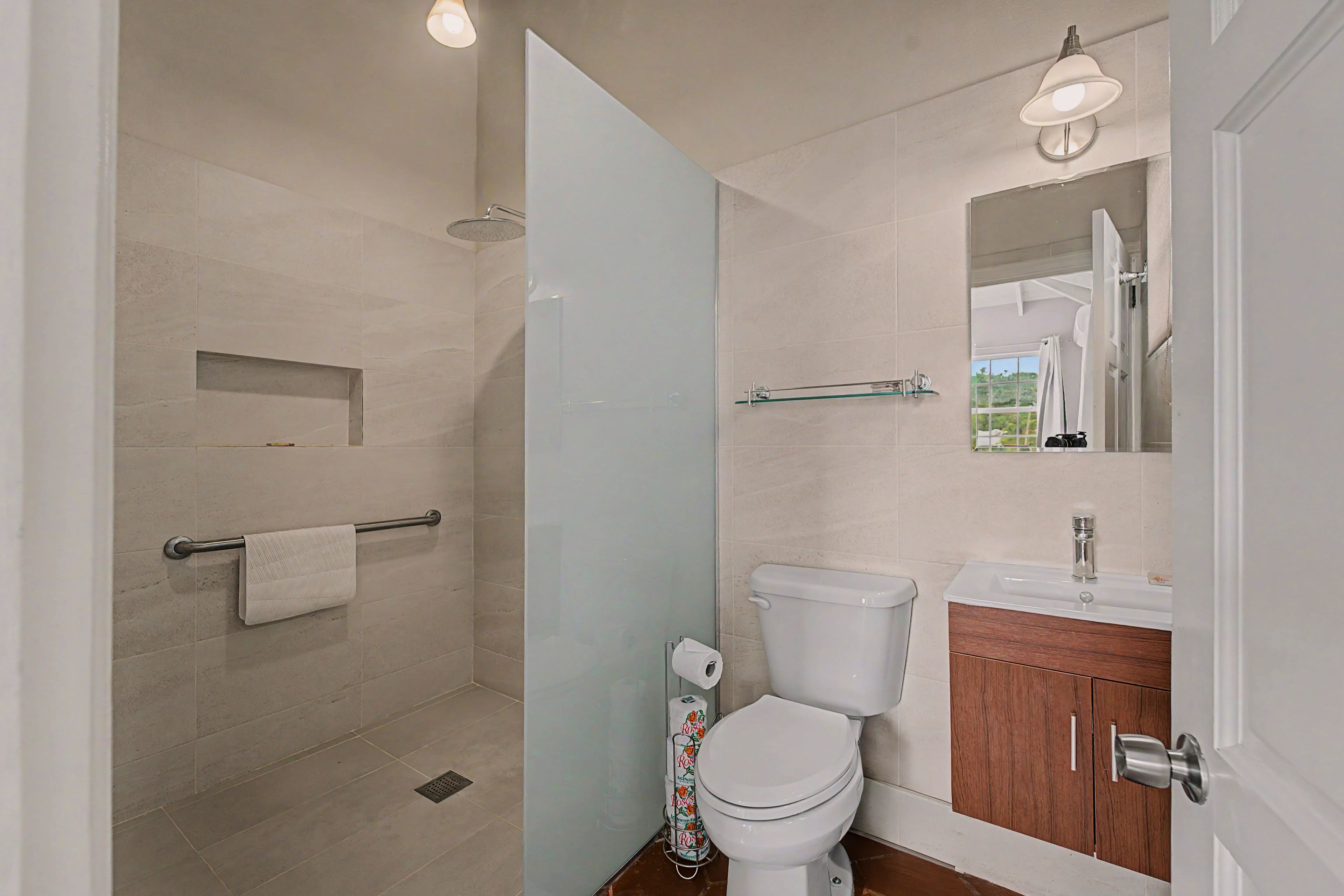 Une salle de bain moderne avec une douche à parois de verre, des toilettes, un lavabo et un miroir.