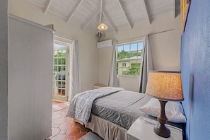 A bedroom with a bed, a bedside table with a lamp, an air conditioning unit, and a window with curtains. - Best E Villas Prospect (Prospect)