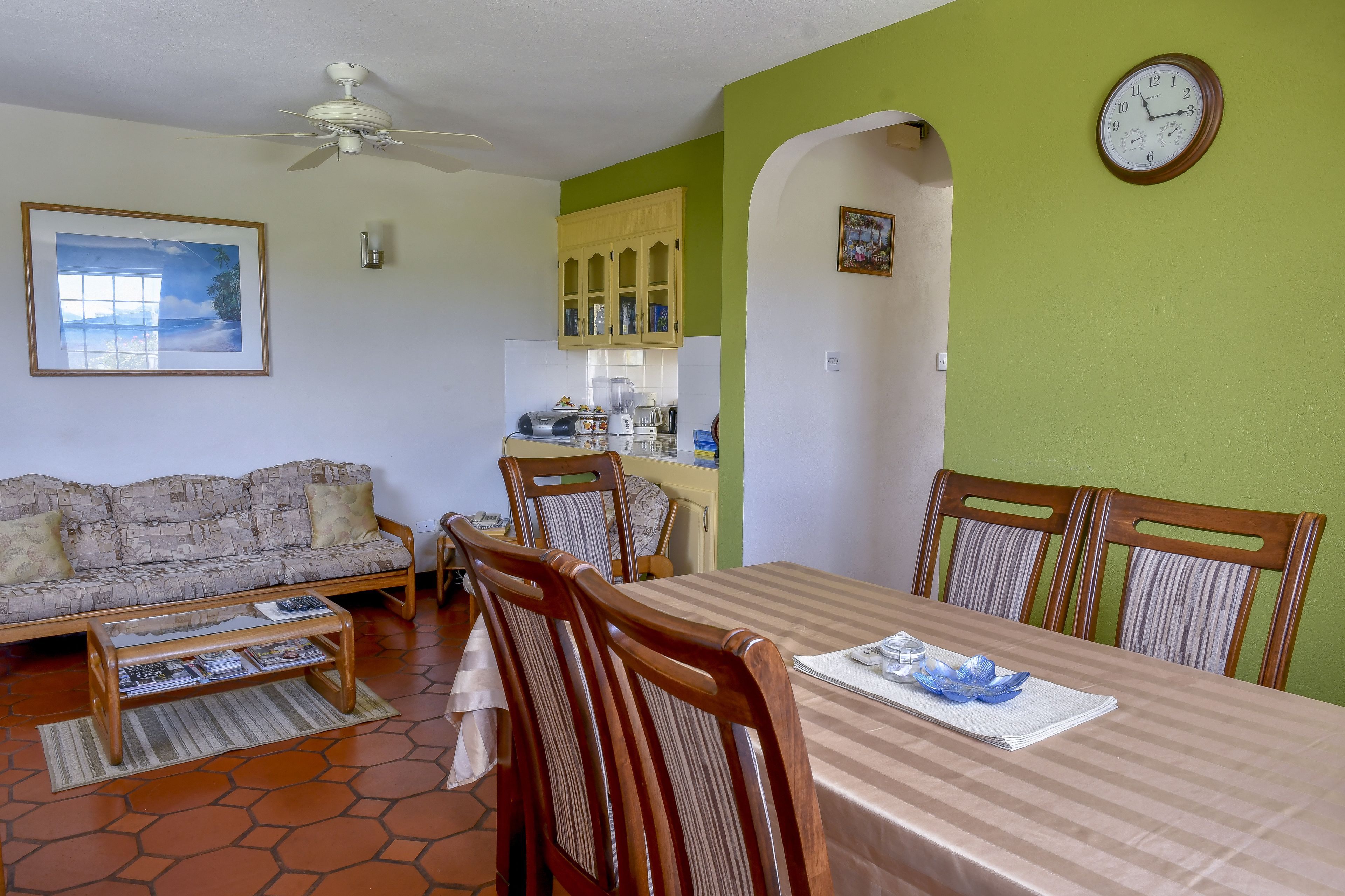 Un comedor con una mesa, sillas y un reloj en la pared.