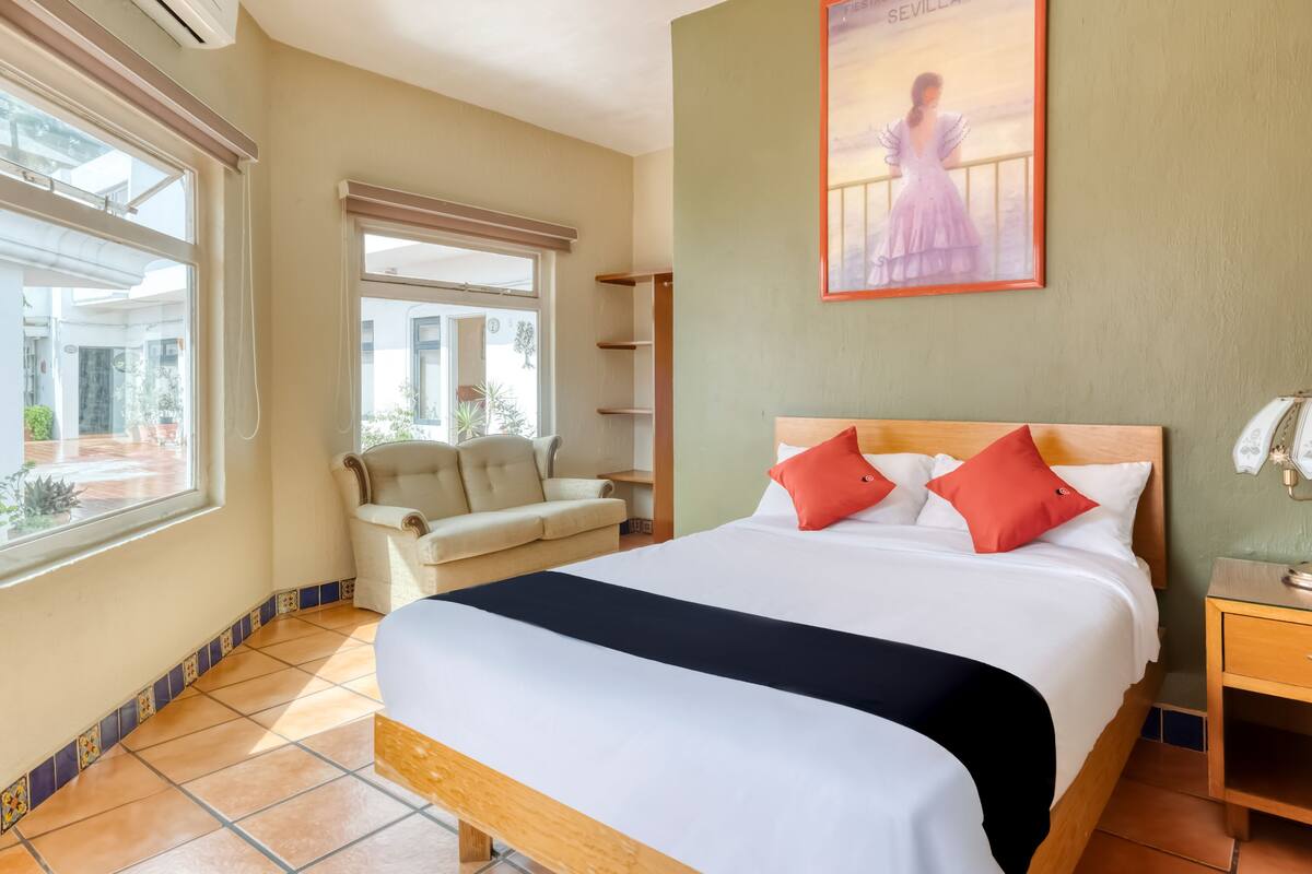 Habitación de hotel con cama, sofá, ventana y un cartel en la pared.