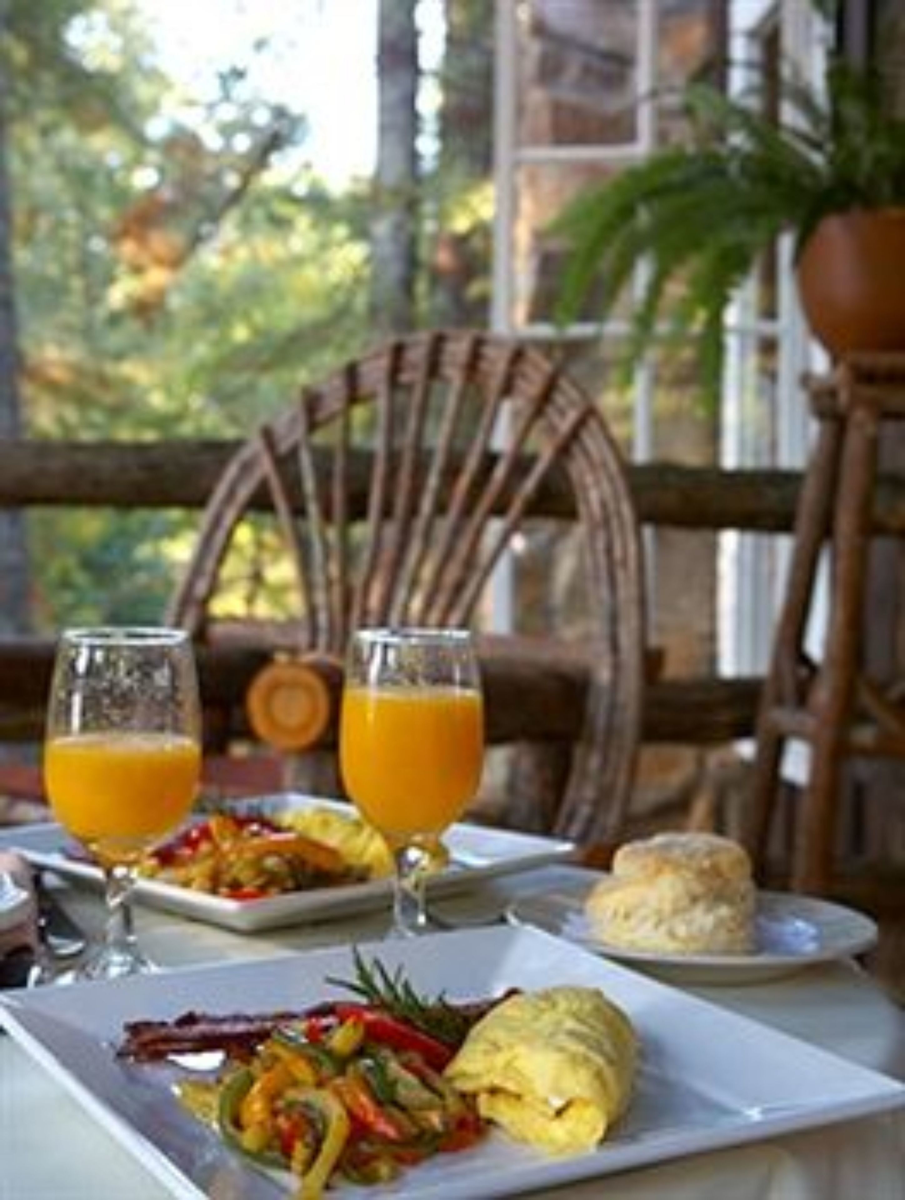A breakfast setting with a plate of food, two glasses of orange juice, and a biscuit on a table.