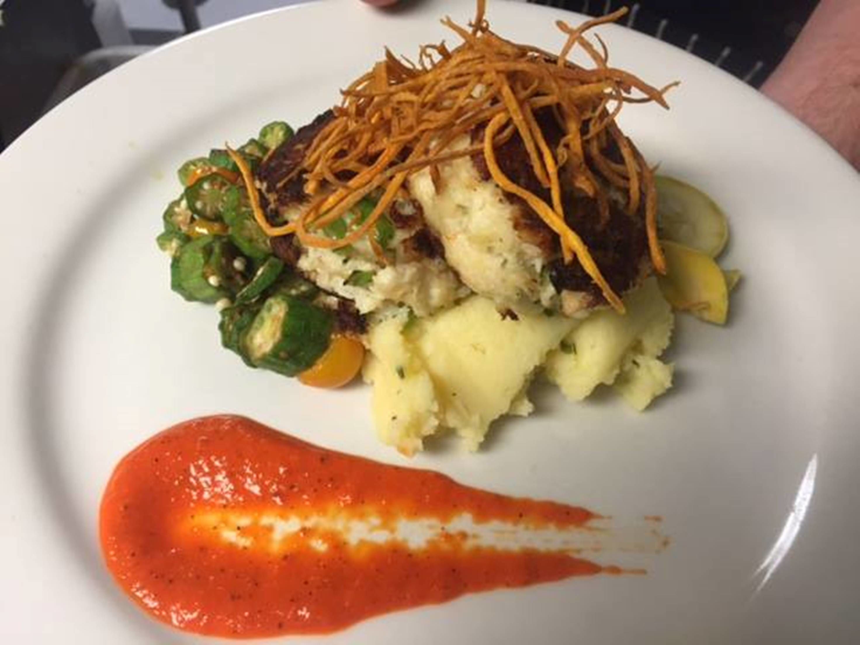 A plate with mashed potatoes, grilled meat, sautéed vegetables, and a dollop of sauce.