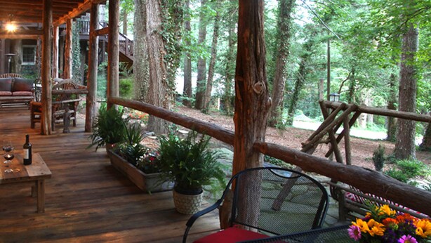 A wooden deck with outdoor seating, surrounded by trees.