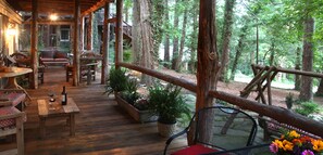 Une terrasse en bois avec des sièges d’extérieur, entourée d’arbres.