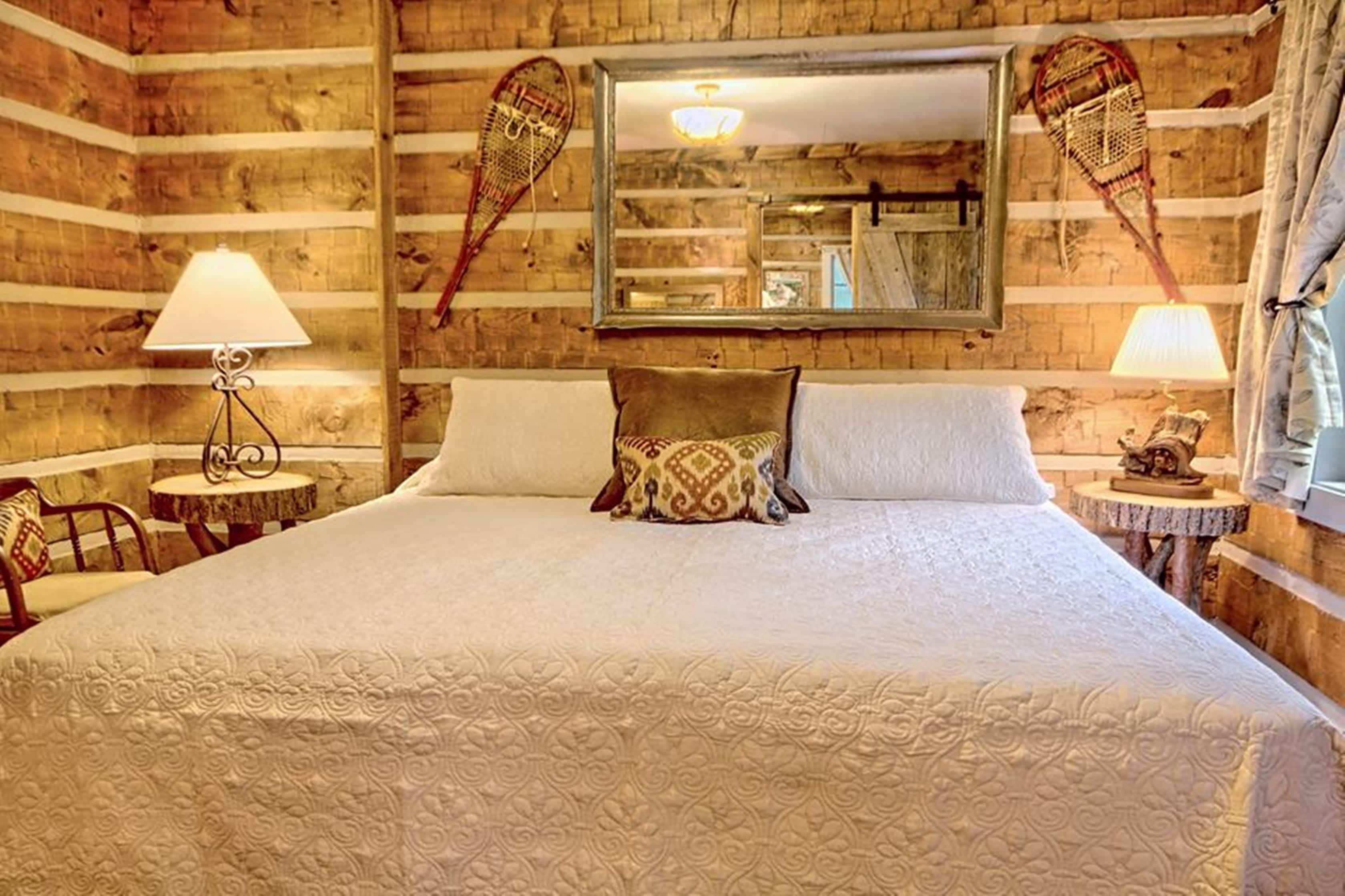 A wooden room with a large bed, two bedside tables, and a mirror on the wall.