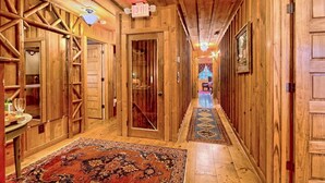 A wooden hallway with a patterned rug, wooden doors, and an exit sign.