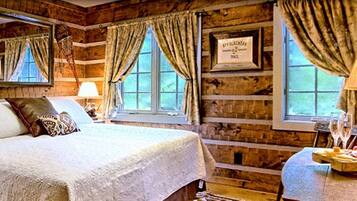 Una stanza rustica in legno con un letto, un tavolo imbandito e una lampada.