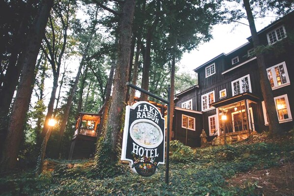 A sign for Lake Rabun Hotel surrounded by tall trees.