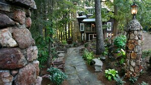 A stone pathway leading to a rustic wooden building surrounded by trees.