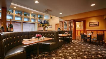 A restaurant with leather booths, a patterned carpet, and a wall of wine bottles.