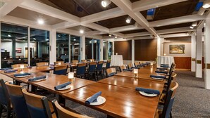 A conference room with wooden tables, blue chairs, and white tablecloths. - Best Western Plus Windjammer Inn & Conference Center (South Burlington)