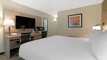 Een hotelkamer met een groot bed, een bureau met een flatscreen televisie, een magnetron en een koffiezetapparaat.