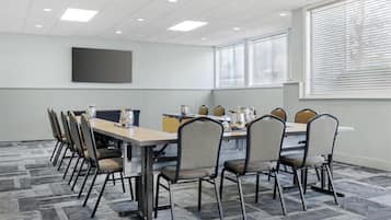 A conference room with a long table, chairs, and a projector screen.