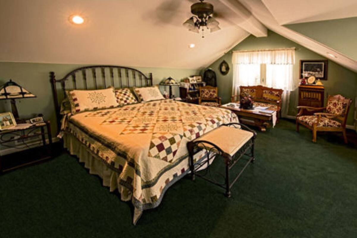 Un dormitorio con una cama grande, una silla, un escritorio y una lámpara.