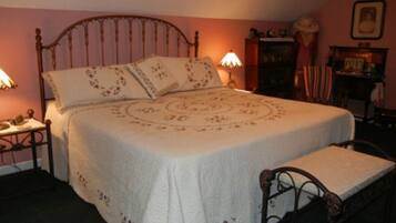 Un dormitorio con cama con dosel, una mesita de noche con lámpara y un banco al pie de la cama.