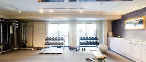 Een sportschool met fitnessapparatuur, gewichten en een roeimachine.