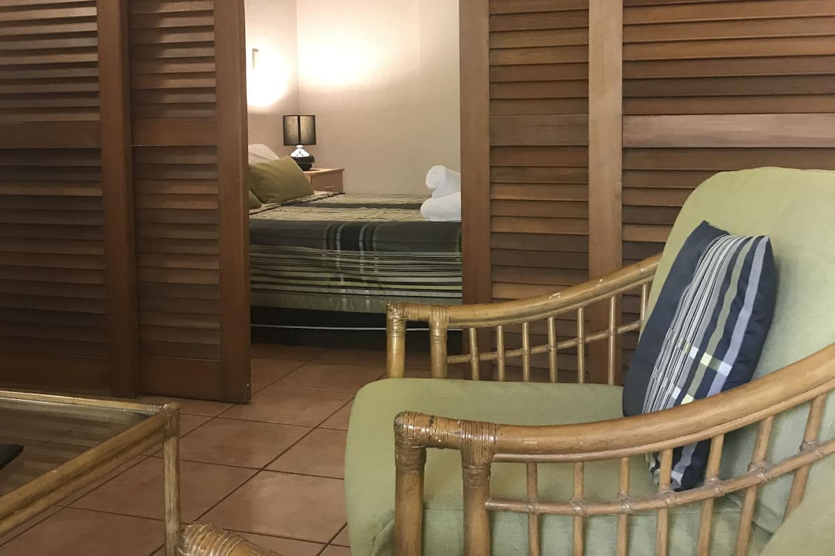 A room with a bed, a chair, a table, and a lamp.