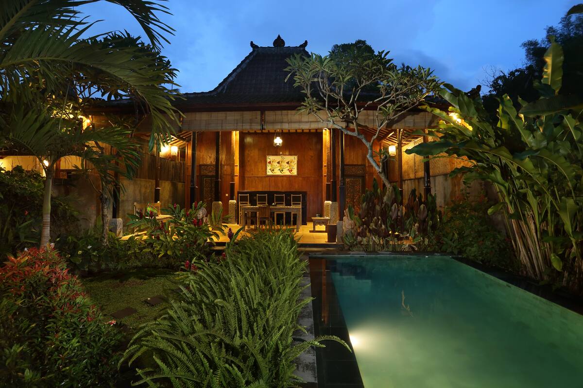 A traditional building with a pool, surrounded by lush greenery and a well-maintained garden.