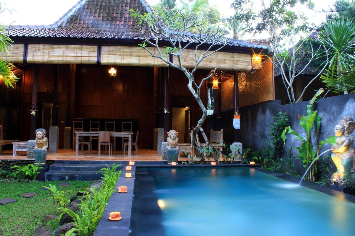 A traditional wooden building with a tiled roof, a pool, and statues.