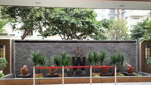 A modern outdoor area with a stone wall, potted plants, and a red barrier. - Wellgold Hotel (Guangzhou)
