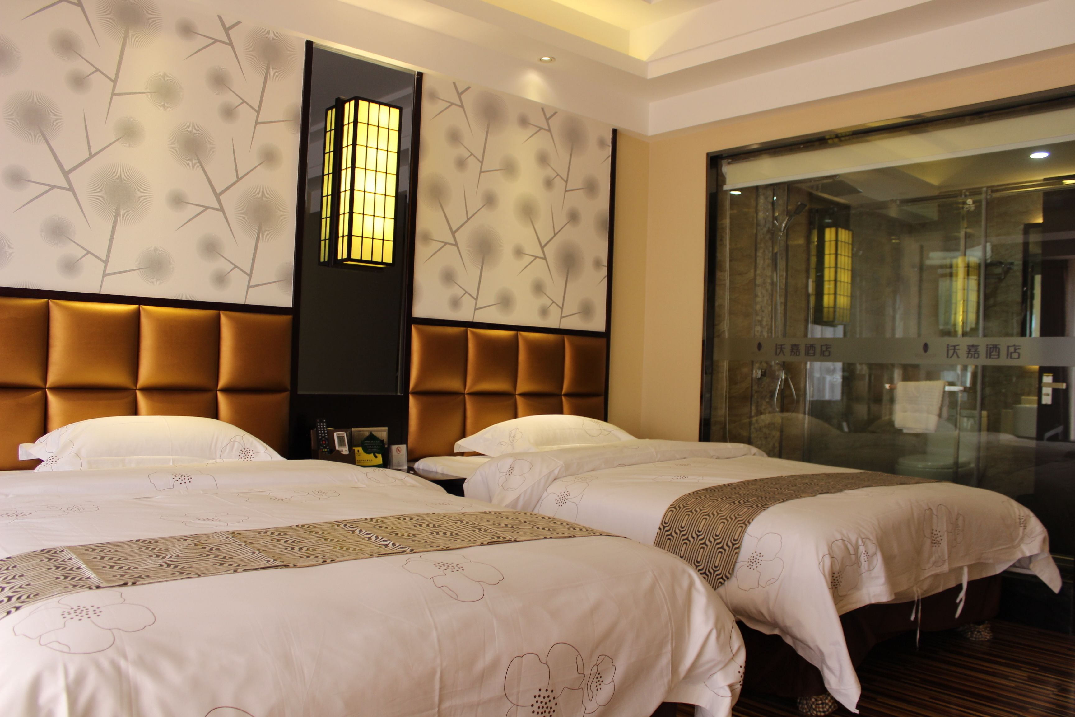 A hotel room with two beds, a large window, and a decorative wall panel.