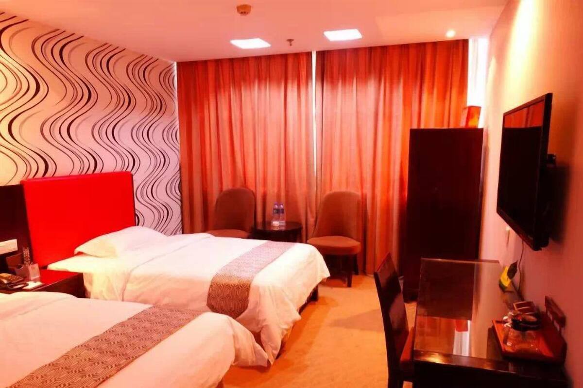 A hotel room with two beds, a TV, a desk, and a chair.
