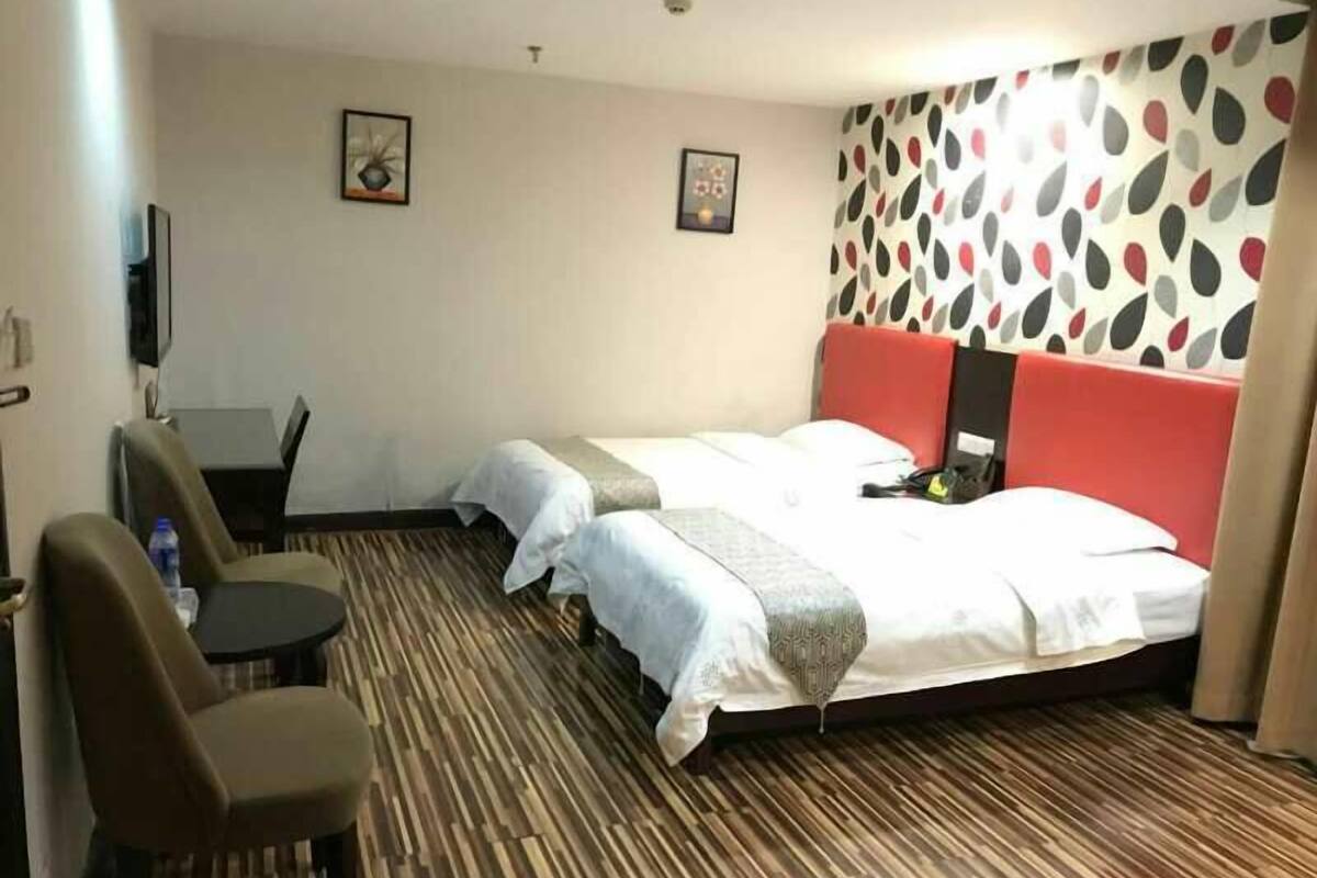 A hotel room with two beds, a desk, and a chair.