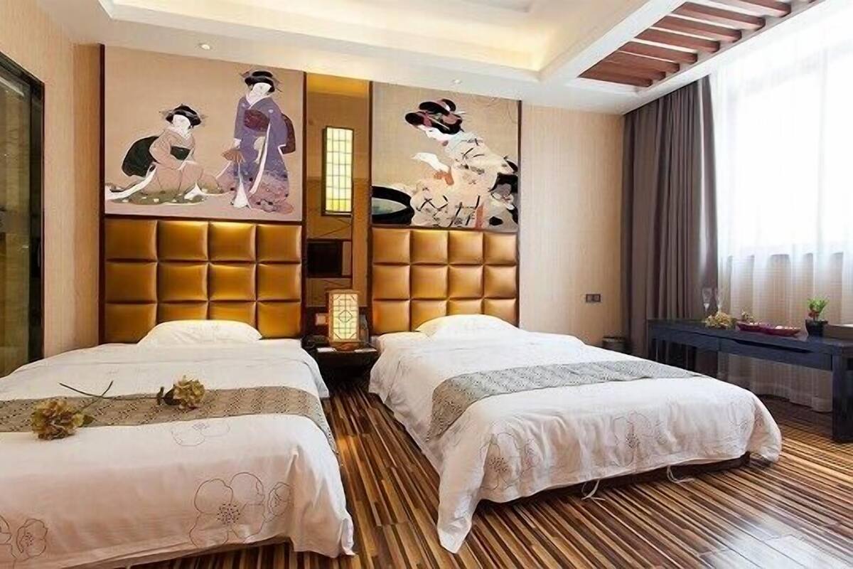 A hotel room with two beds, a large padded headboard, and traditional artwork on the wall.