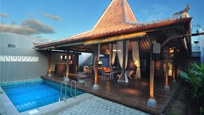 A poolside area with a covered seating area, a swimming pool, and a building with a tiled roof. - d'Lima Hotel & Villas (Kuta)