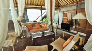 A spacious living area with a sofa, two wicker chairs, a coffee table, and a television. - d'Lima Hotel & Villas (Kuta)