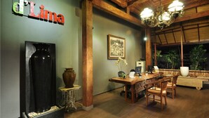 A dining area with a wooden table, chairs, a chandelier, and a large vase. - d'Lima Hotel & Villas (Kuta)