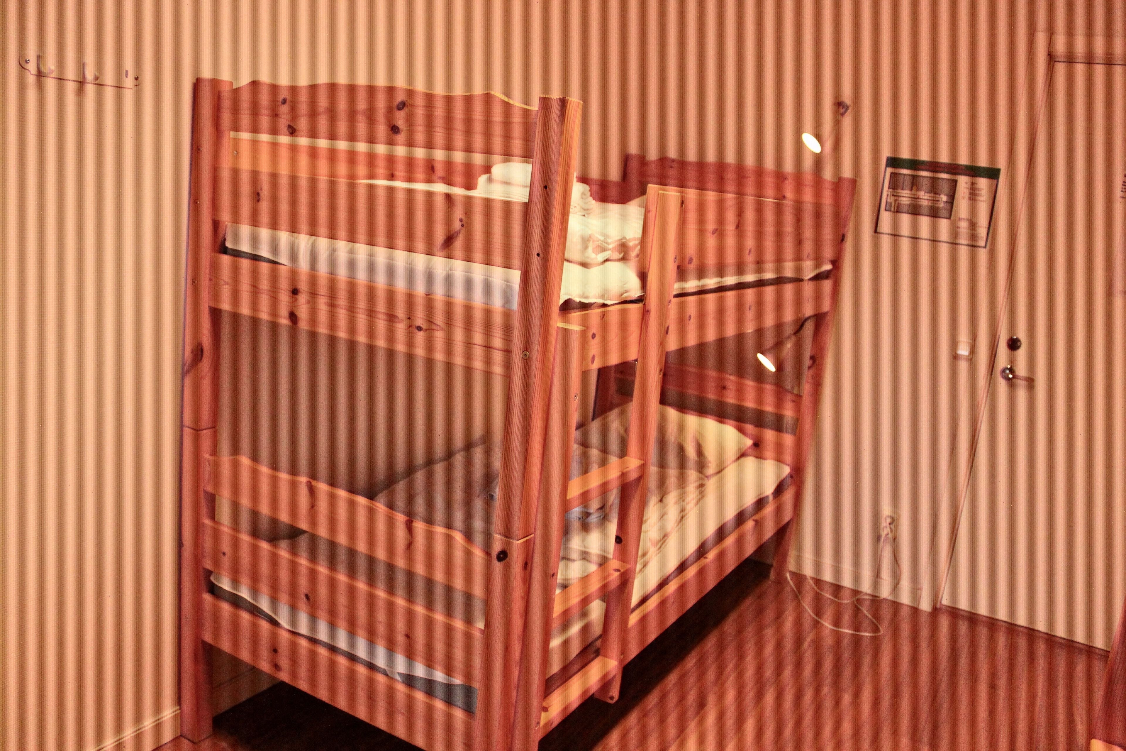 A room with two bunk beds, a door, and a light switch on the wall.