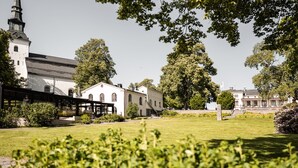 A church with a steeple, surrounded by greenery and adjacent buildings. - Lindesbergs Stadshotell (Lindesberg)