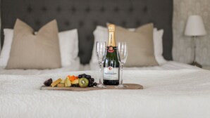 A bed with a champagne bottle and glasses on a tray, accompanied by fruit. - Lindesbergs Stadshotell (Lindesberg)