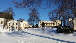 A snow-covered street with historic buildings, including a large mansion with a symmetrical facade and arched windows. - Lindesbergs Stadshotell (Lindesberg)