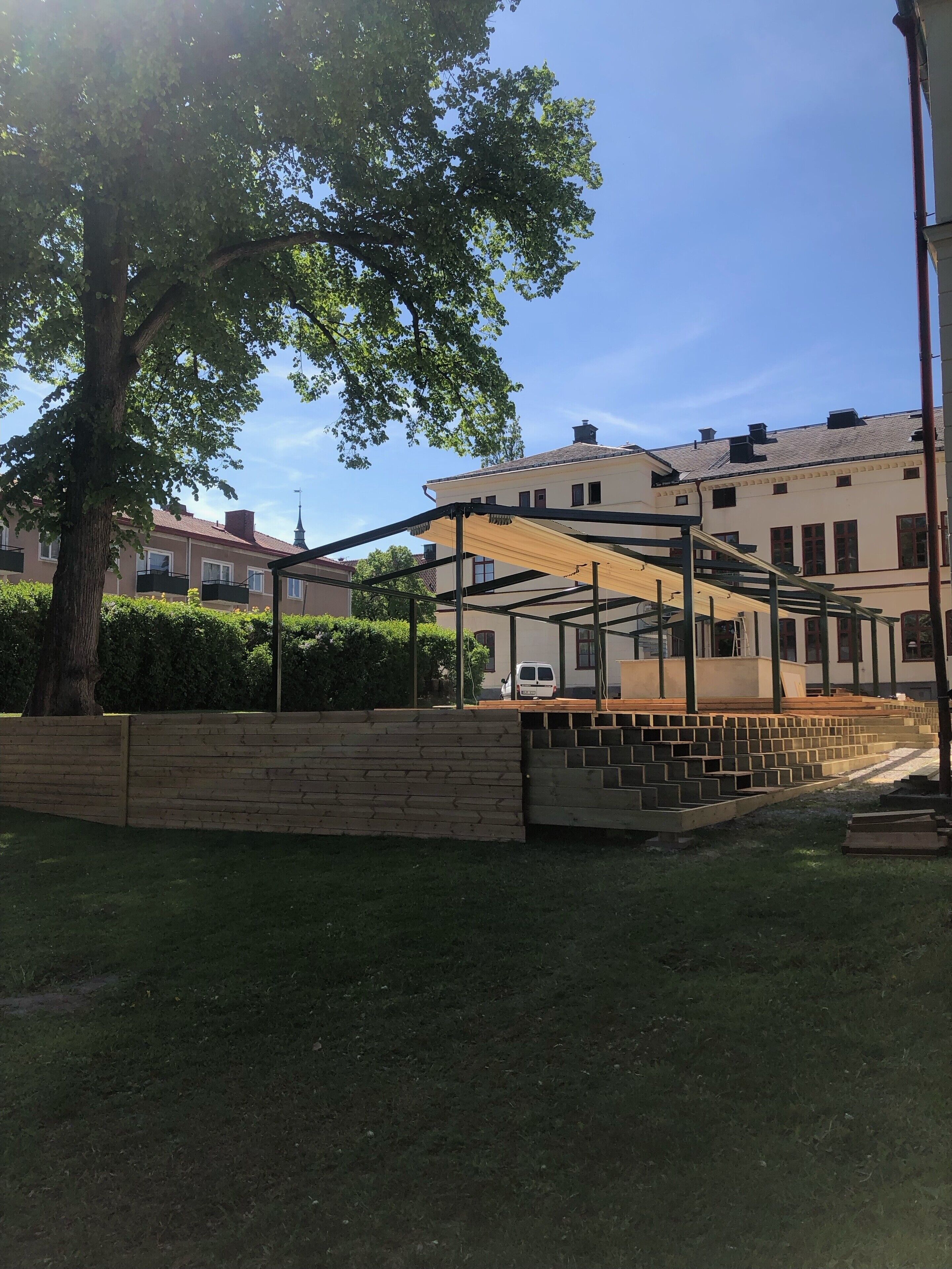 A courtyard with a wooden fence, a tree, and a building with multiple windows and balconies.