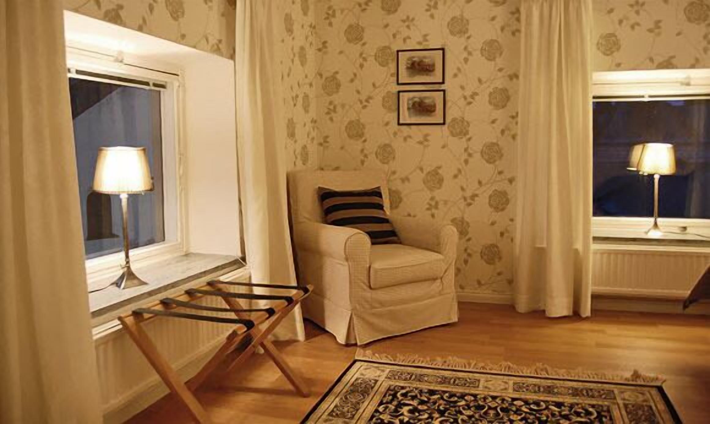 A cozy room with a chair near a window, a radiator, and a patterned rug.