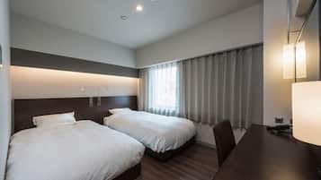 A hotel room with two beds, a desk, and a window with curtains.