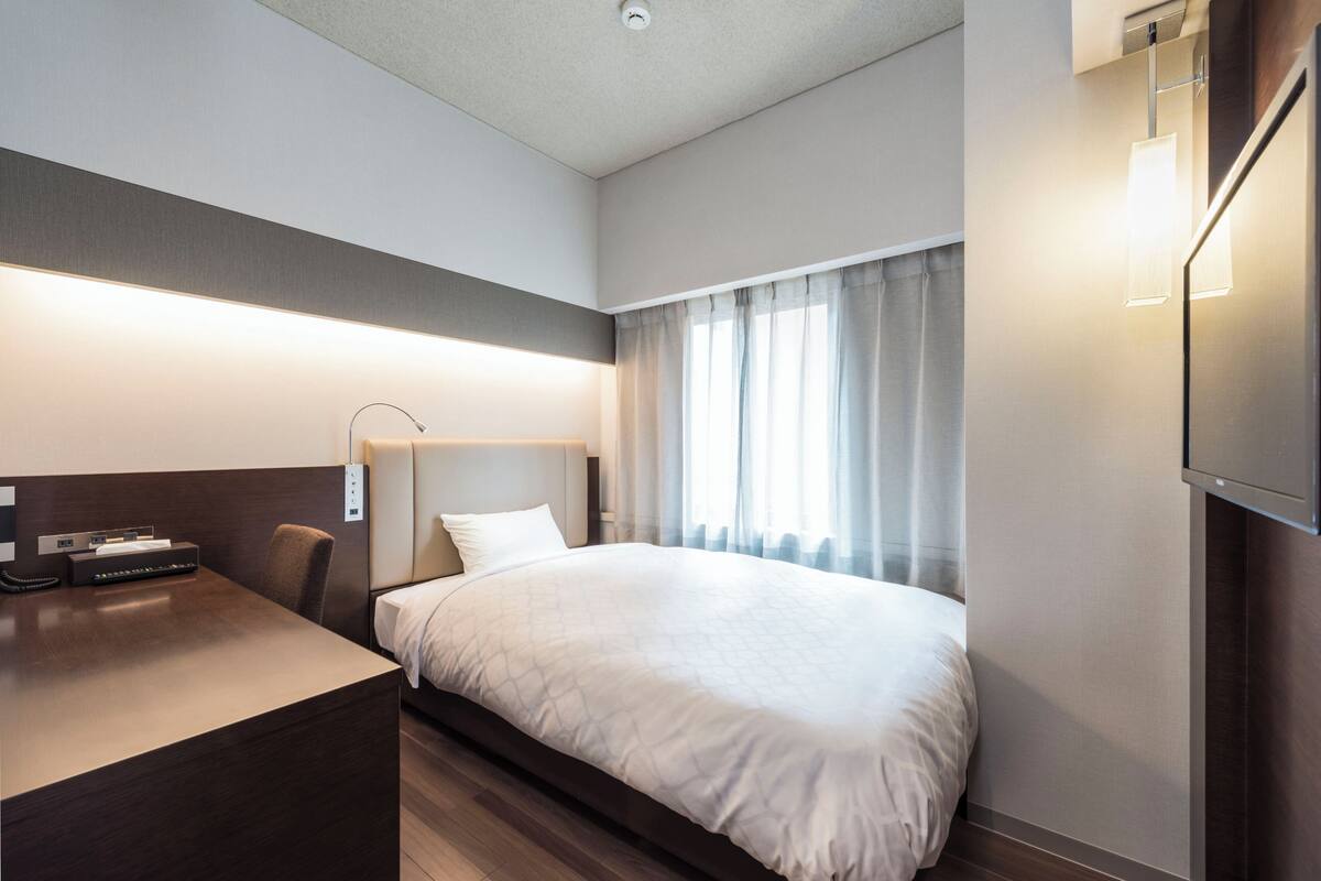 Een hotelkamer met een bed, bureau en televisie.