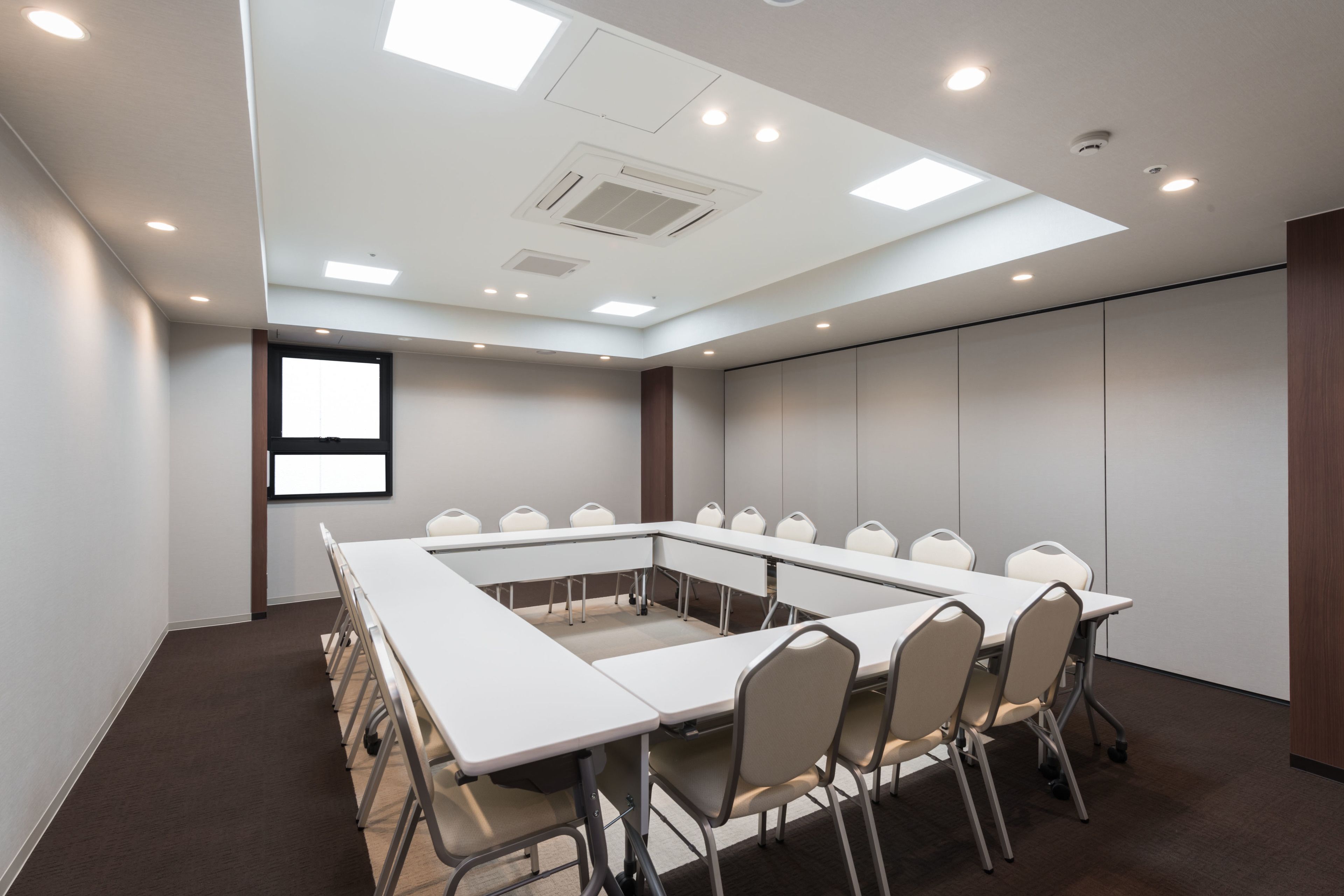 A conference room with a long table, chairs, and a projector screen.
