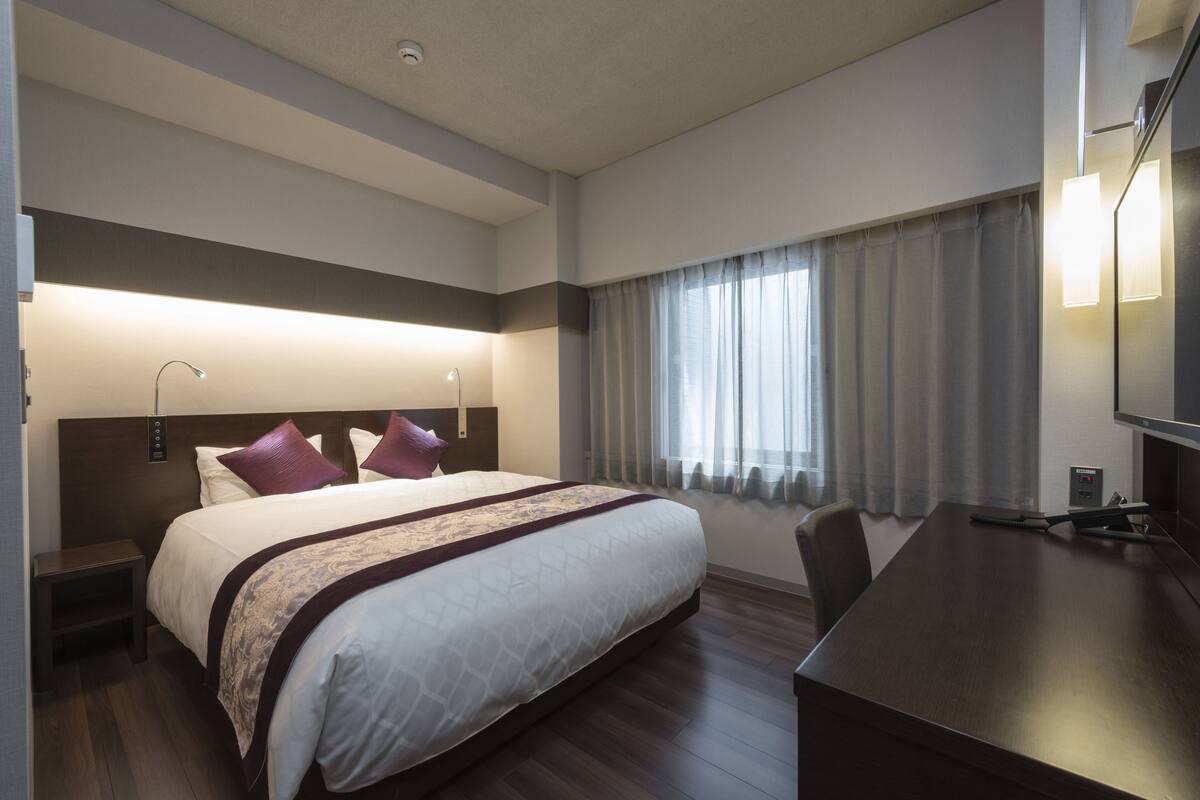 Een hotelkamer met een groot bed, een bureau en een stoel.