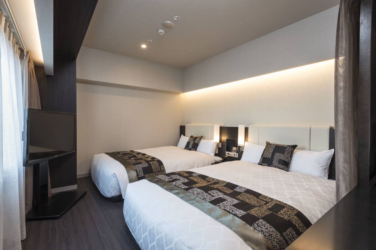 Een moderne hotelkamer met twee bedden, een flatscreen televisie en een inbouwkast.